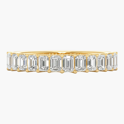 Gold ring with emerald-cut diamonds on a white background