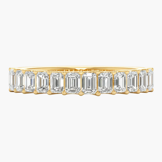 Gold ring with emerald-cut diamonds on a white background