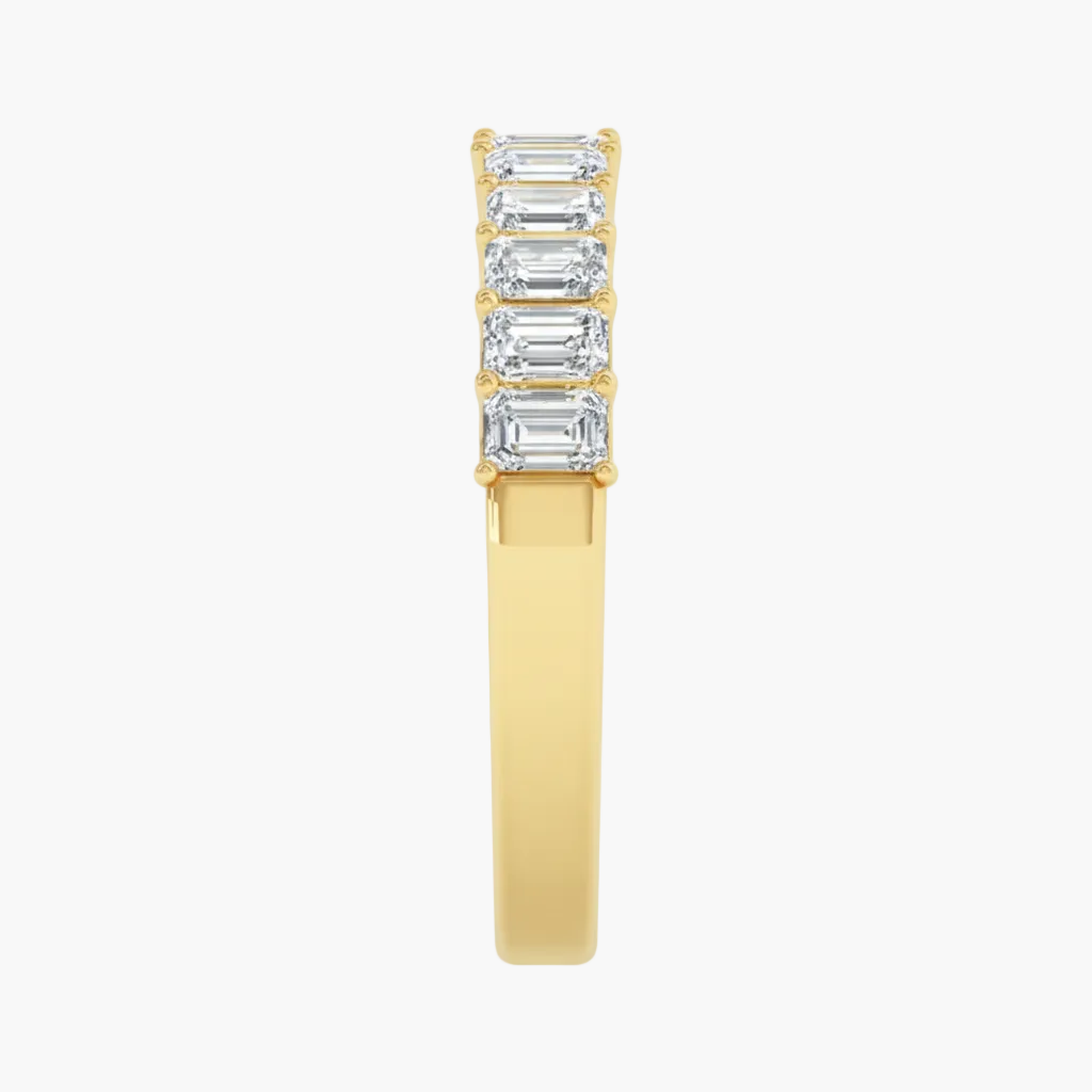 Gold ring with emerald-cut gemstones on a white background