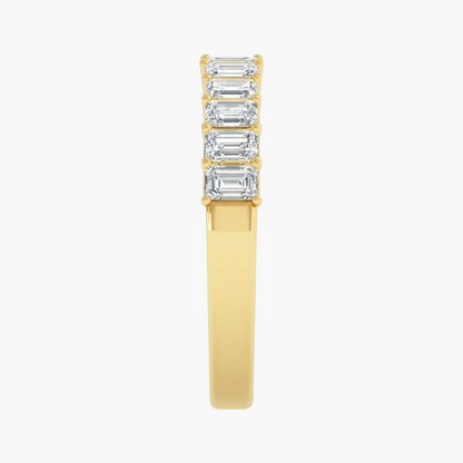Gold ring with emerald-cut gemstones on a white background
