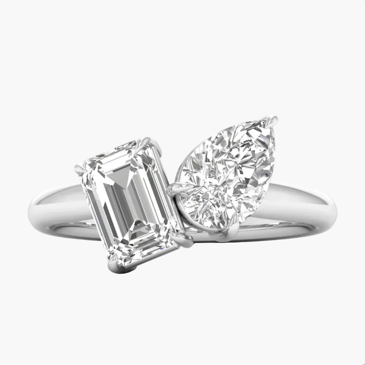 Diamond ring with emerald-cut and pear-shaped gemstones on a white background