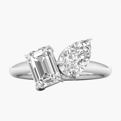 Diamond ring with emerald-cut and pear-shaped gemstones on a white background