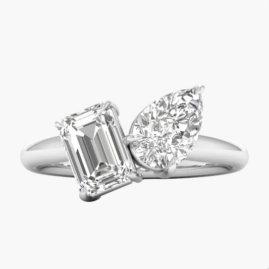 Diamond ring with emerald-cut and pear-shaped gemstones on a white background
