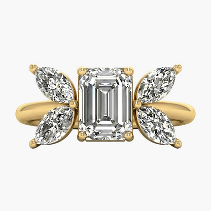 Gold ring with emerald-cut diamond and pear-shaped side stones on a white background
