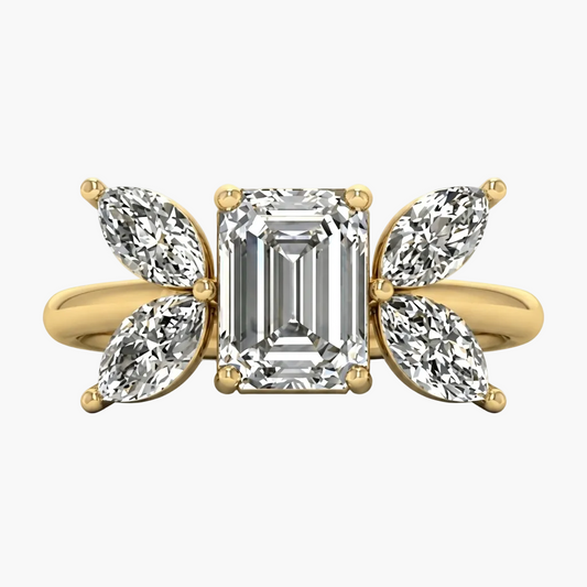Gold ring with emerald-cut diamond and pear-shaped side stones on a white background