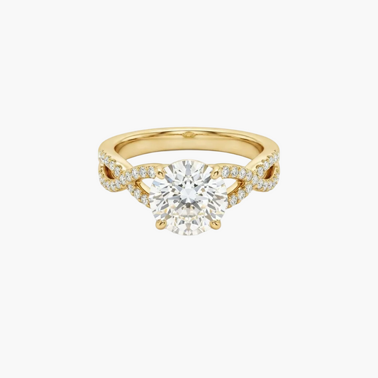 A yellow gold engagement ring featuring a round brilliant-cut center stone and pavé-set accent stones along a split shank, shown on a light gray background.