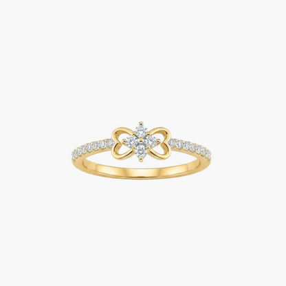 A yellow gold ring featuring a bow-shaped centerpiece with a small cluster of clear stones in the center and a pavé band with small round stones, shown on a light gray background.