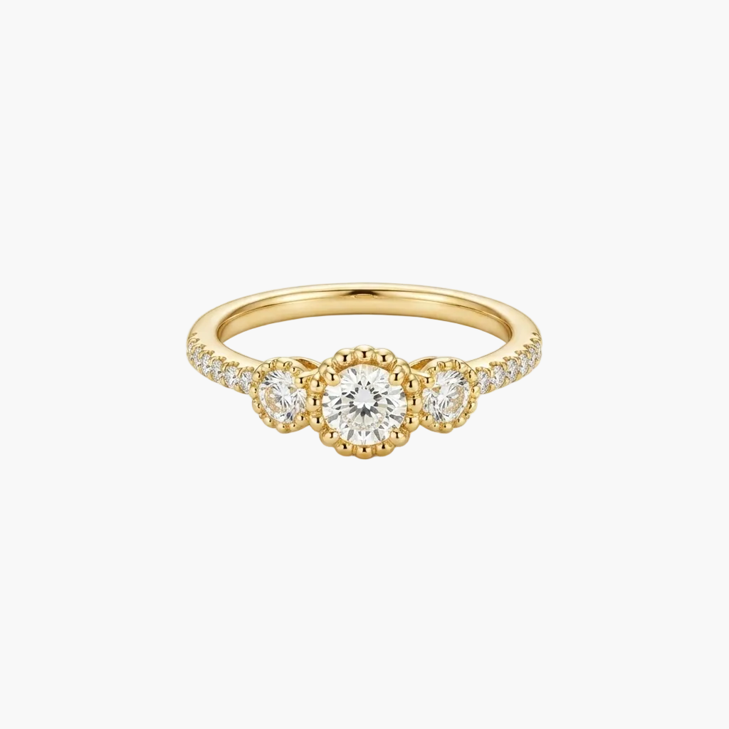 A yellow gold three-stone ring featuring a central round brilliant-cut diamond flanked by two smaller round diamonds, with small pavé diamonds along the shoulders, set against a clean white background.