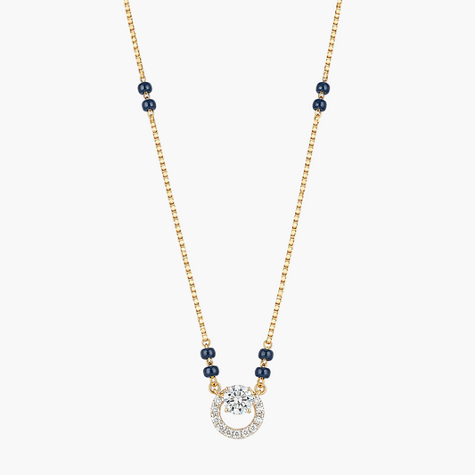A delicate gold chain necklace featuring small dark blue beads spaced along the chain and a central pendant. The pendant consists of a clear round gemstone surrounded by a halo of small clear stones, set in a gold and white metal frame, against a plain white background.