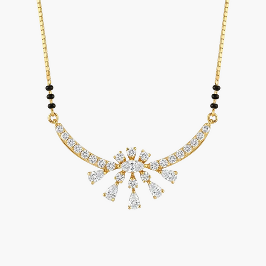 Gold necklace with a curved pavé pendant featuring a central starburst design of clear teardrop and round stones, accented by small black beads on the chain, shown on a light gray background.