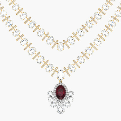 Gold necklace with clear gemstones and a red gemstone pendant on a white background