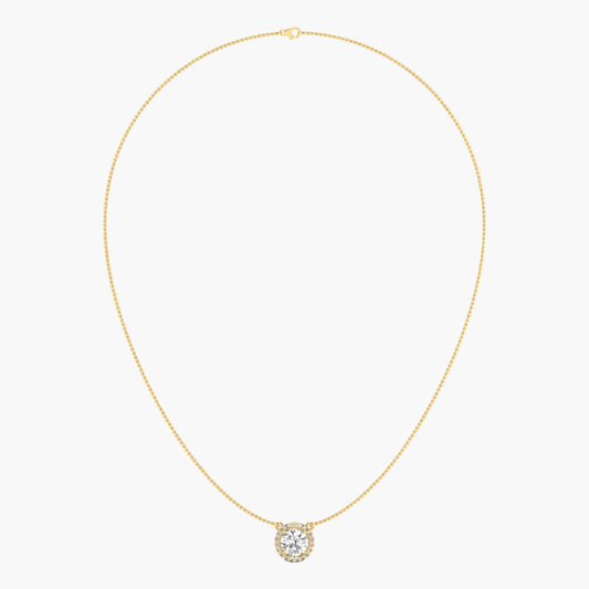 Gold necklace with a round pendant on a light beige background