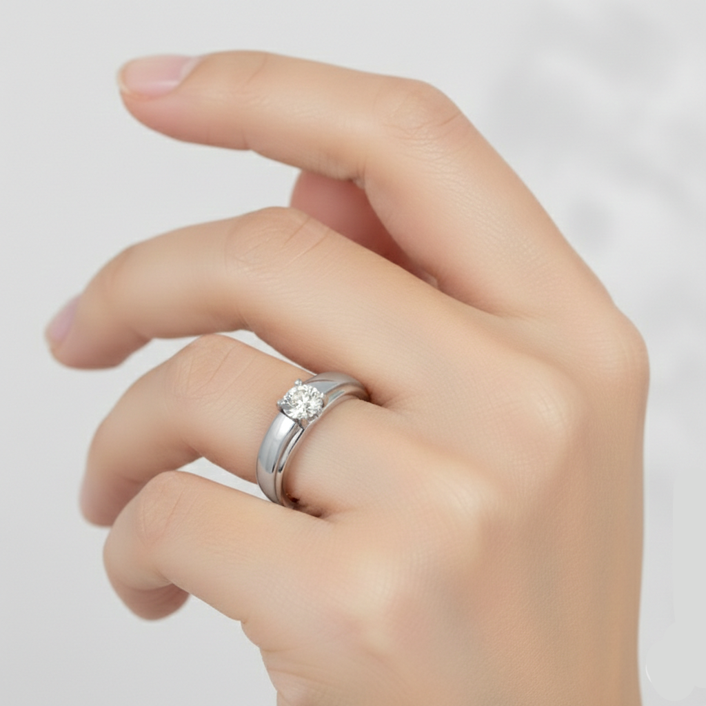 Hand wearing a silver ring with a diamond on a light gray background