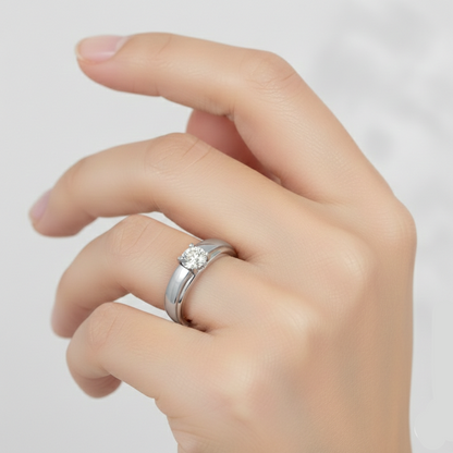 Hand wearing a silver ring with a diamond on a light gray background