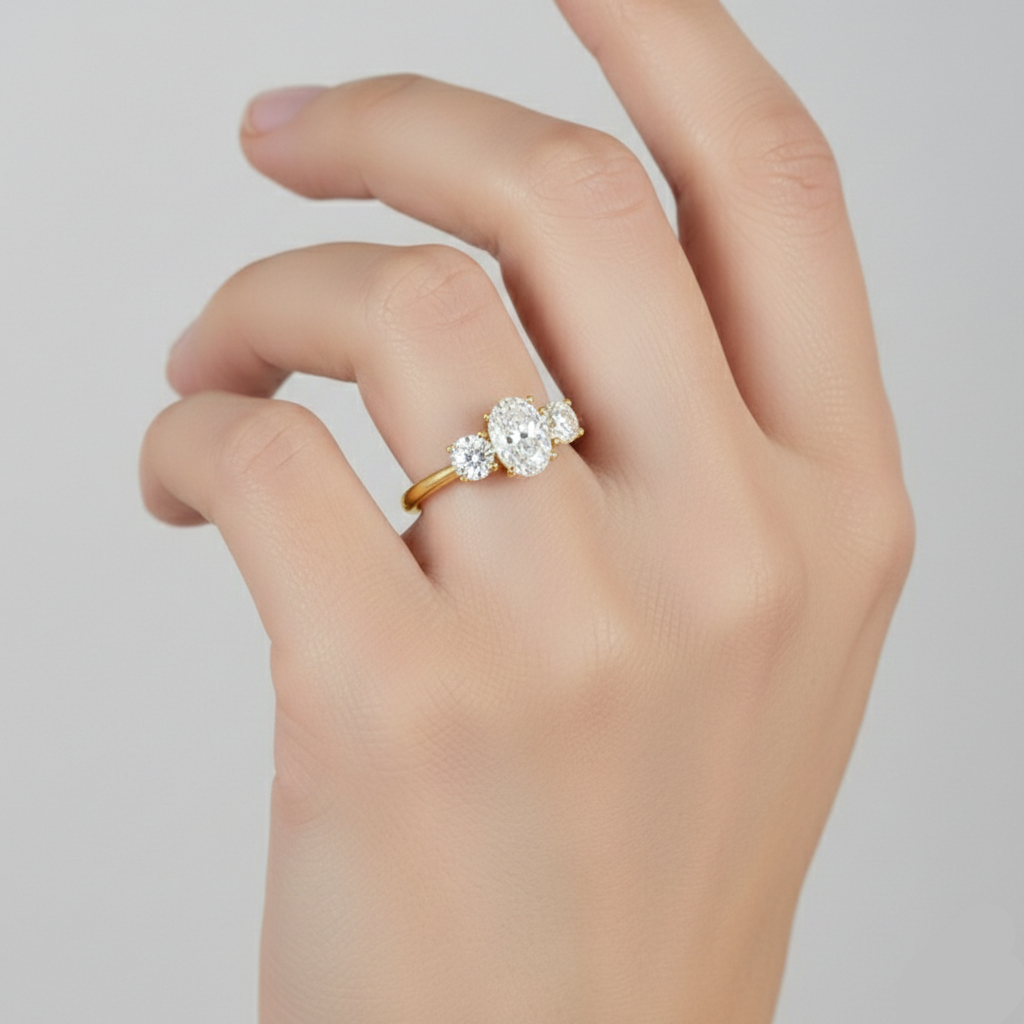 Gold ring with three diamonds on a hand against a light gray background