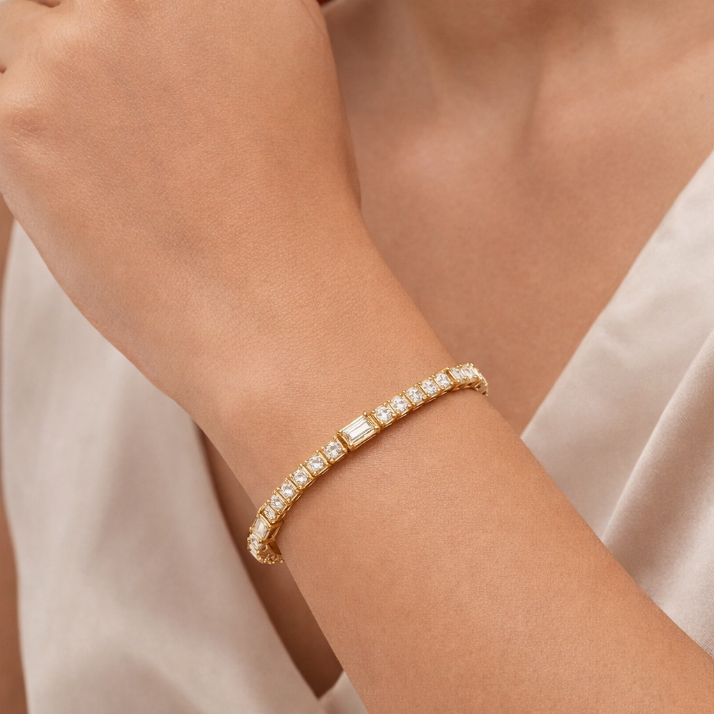 Gold bracelet with diamonds on a person's wrist against a neutral background