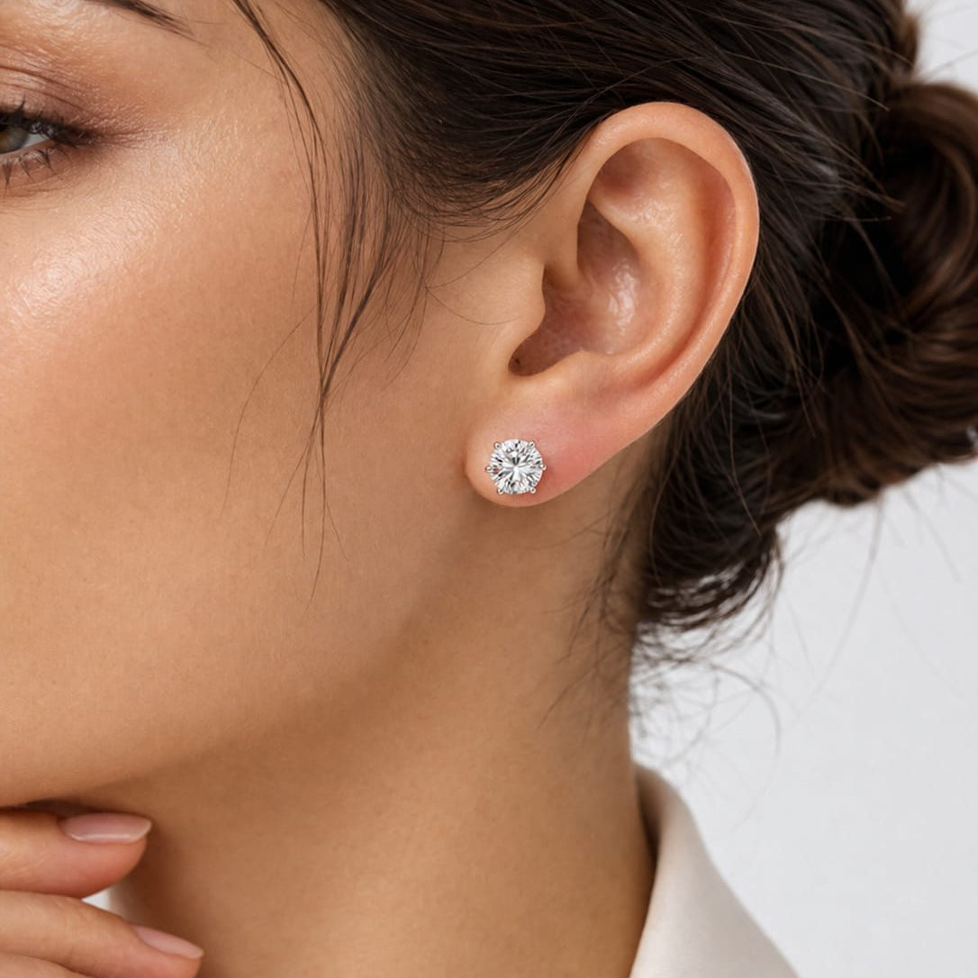 Close-up of a woman wearing diamond stud earrings with a blurred background