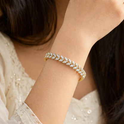 Gold bracelet with diamonds on a person's wrist, wearing a white lace top.