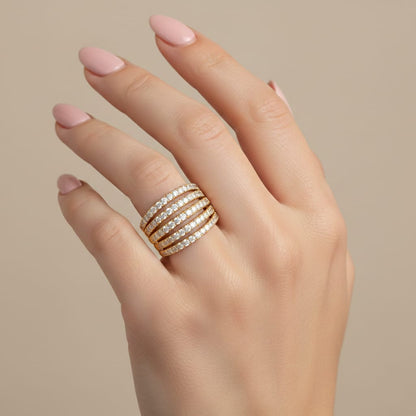 Hand wearing a stack of diamond rings on a beige background