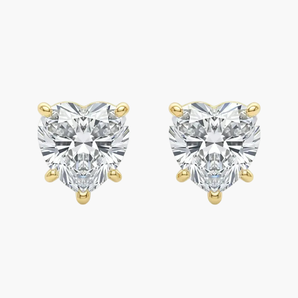 Heart-shaped diamond earrings with gold prongs on a white background