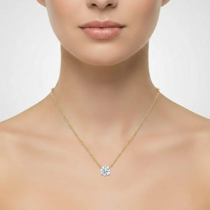 Gold necklace with a diamond pendant worn by a model on a plain background