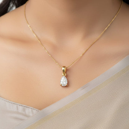 Gold necklace with a teardrop-shaped diamond pendant on a neutral background