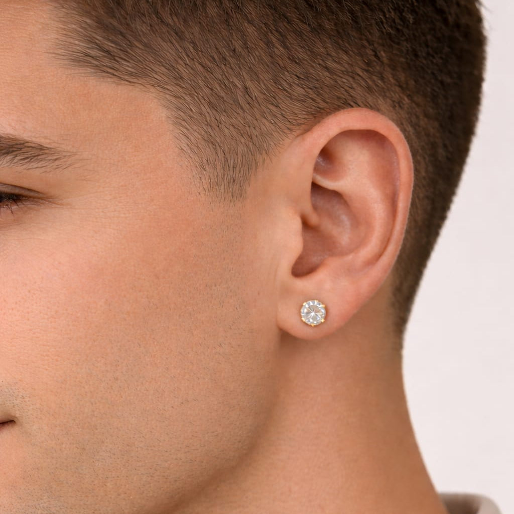 Close-up of a person wearing a diamond stud earring on a plain background