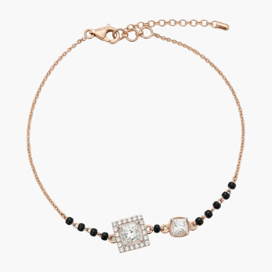 Rose gold bracelet with black beads and square gemstones on a white background