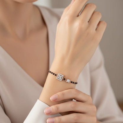 Close-up of a hand wearing a bracelet with a diamond on a neutral background