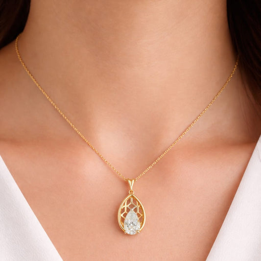 Gold necklace with a teardrop-shaped pendant on a person wearing a white top.