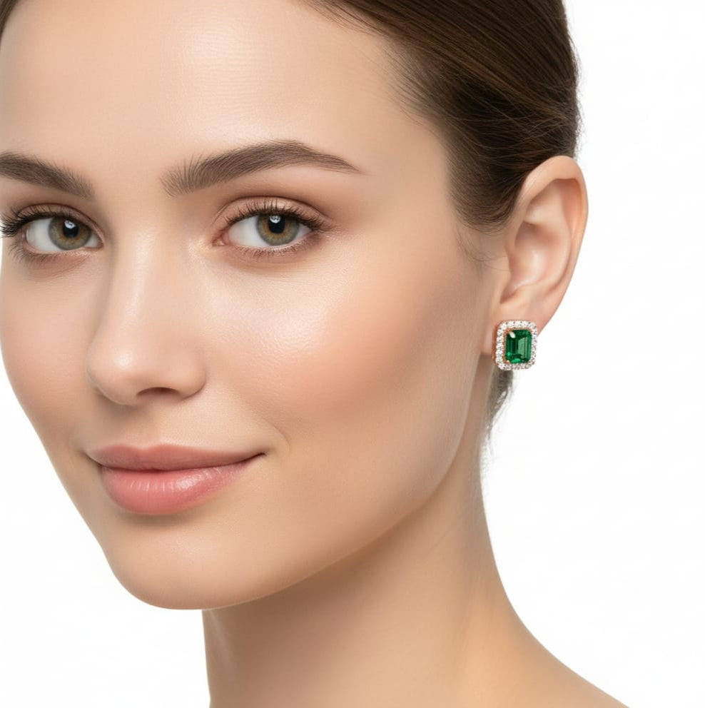 Close-up of a woman wearing emerald green earrings on a white background