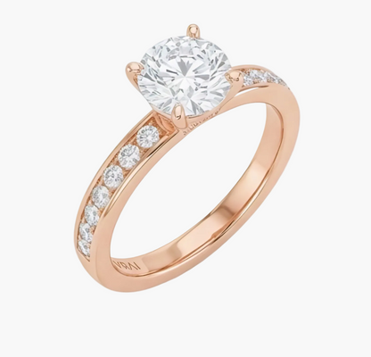 Rose gold ring with a large diamond and smaller diamonds on the band against a white background