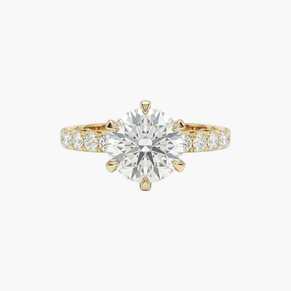 Gold ring with a large diamond and smaller diamonds on the band against a white background