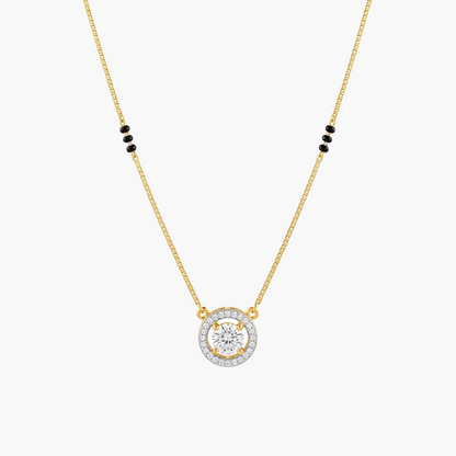 A gold chain necklace with a circular pendant featuring a central clear gemstone surrounded by a halo of small clear stones, with small black bead accents on the chain, shown on a plain white background.