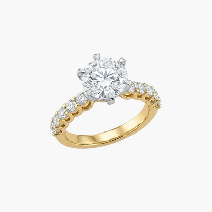 Gold ring with a large diamond and smaller diamonds on the band against a white background
