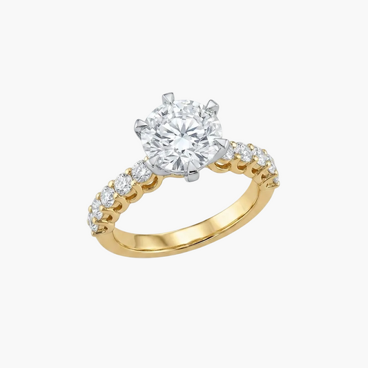 Gold ring with a large diamond and smaller diamonds on the band against a white background