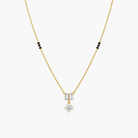 A delicate yellow gold chain necklace featuring a pendant with baguette-cut clear stones and a central round-cut clear stone, accented by small black beads on the chain, shown against a plain white background.