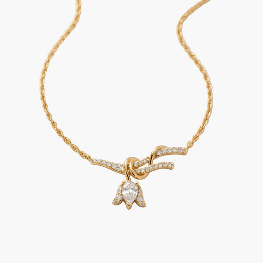 Gold necklace with a bow-shaped pendant on a white background
