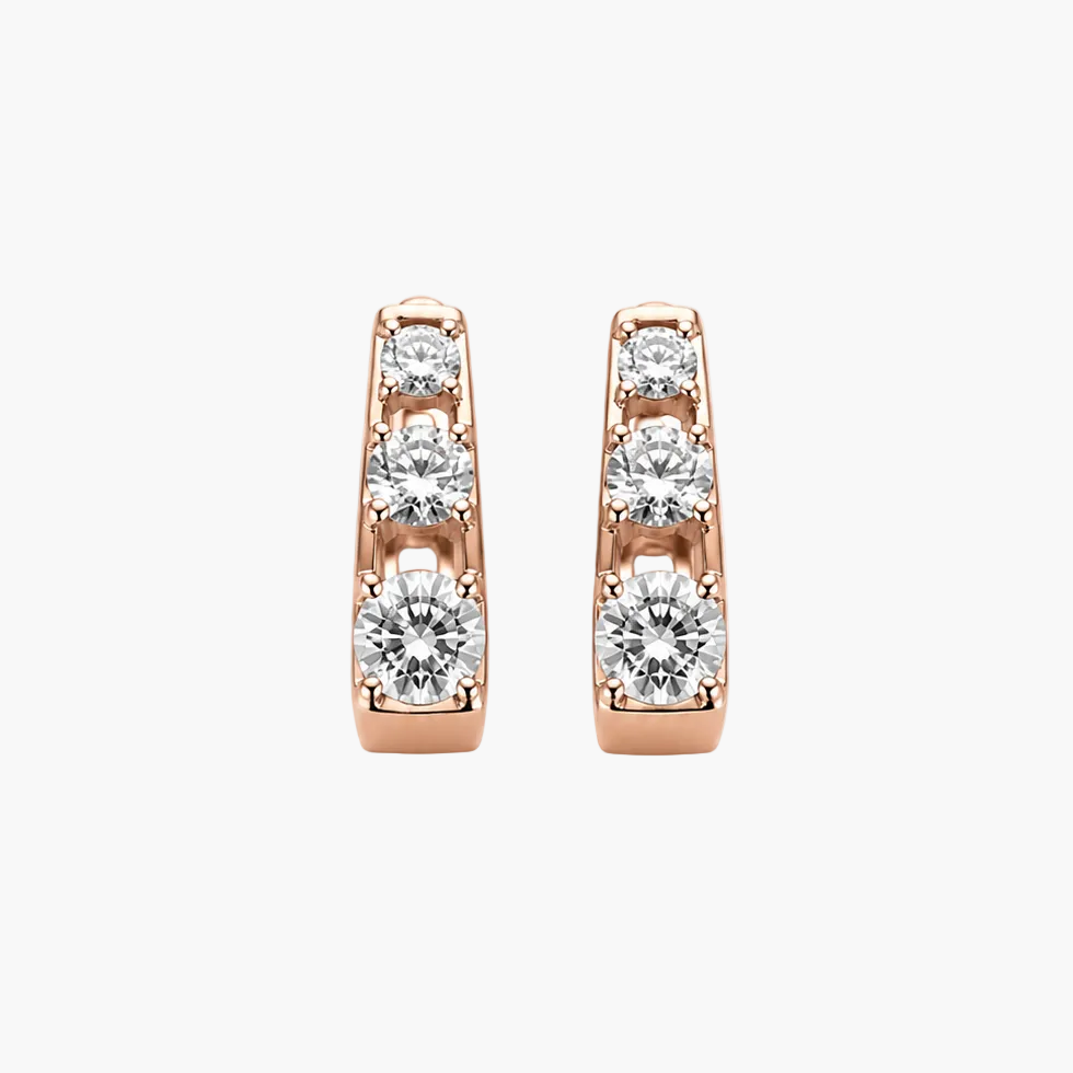 A pair of rose gold huggie hoop earrings with a channel setting of clear round-cut gemstones, shown against a plain white background.