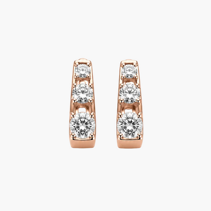 A pair of rose gold huggie hoop earrings with a channel setting of clear round-cut gemstones, shown against a plain white background.