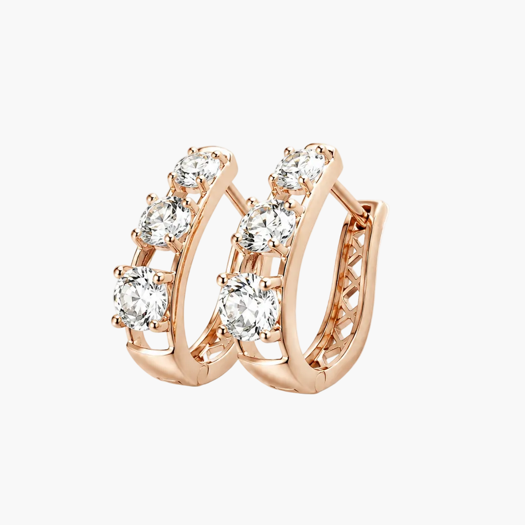 Rose gold huggie hoop earrings with a row of clear round-cut gemstones, shown on a plain white background.