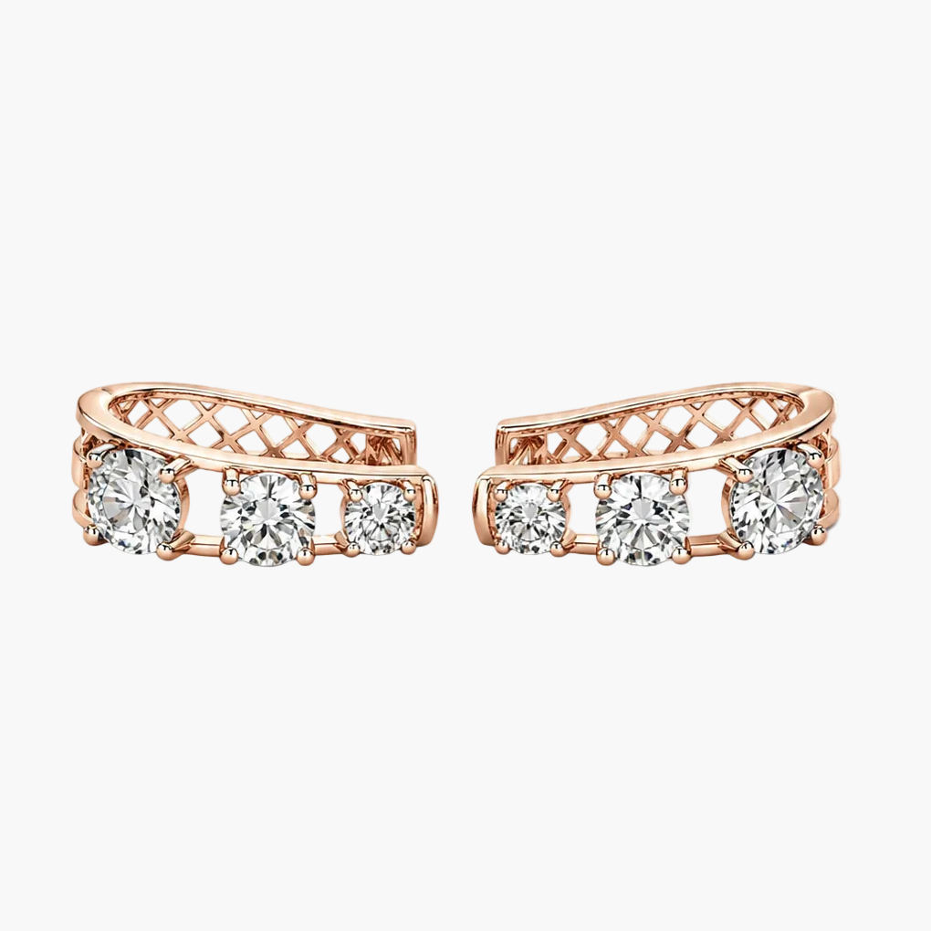 A pair of rose gold huggie hoop earrings with three clear round-cut diamonds on each earring, set against a plain white background.