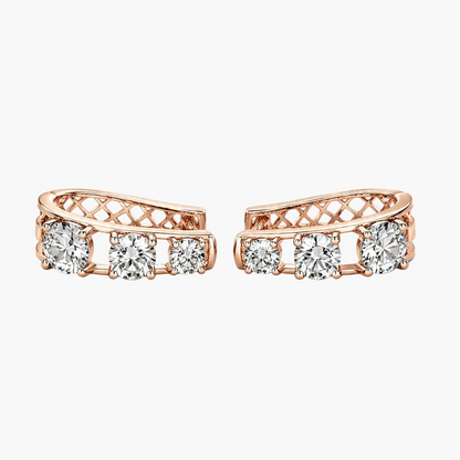A pair of rose gold huggie hoop earrings with three clear round-cut diamonds on each earring, set against a plain white background.