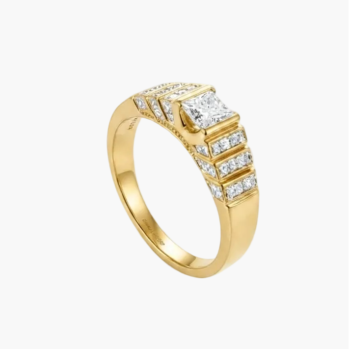 A yellow gold ring featuring a pavé-set diamond band with a central rectangular diamond, photographed on a clean white background.