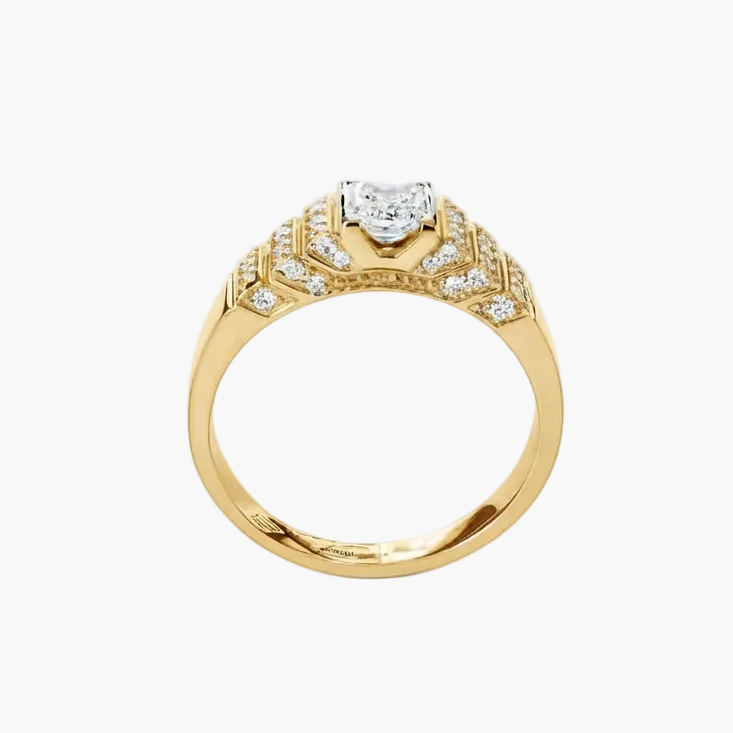 A yellow gold ring with a heart-shaped clear gemstone in the center and smaller pavé-set diamonds along the shoulders, shown on a plain white background.