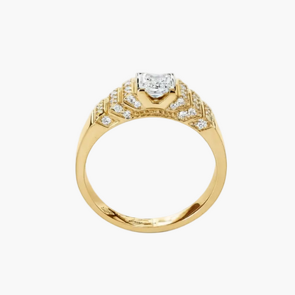 A yellow gold ring with a heart-shaped clear gemstone in the center and smaller pavé-set diamonds along the shoulders, shown on a plain white background.
