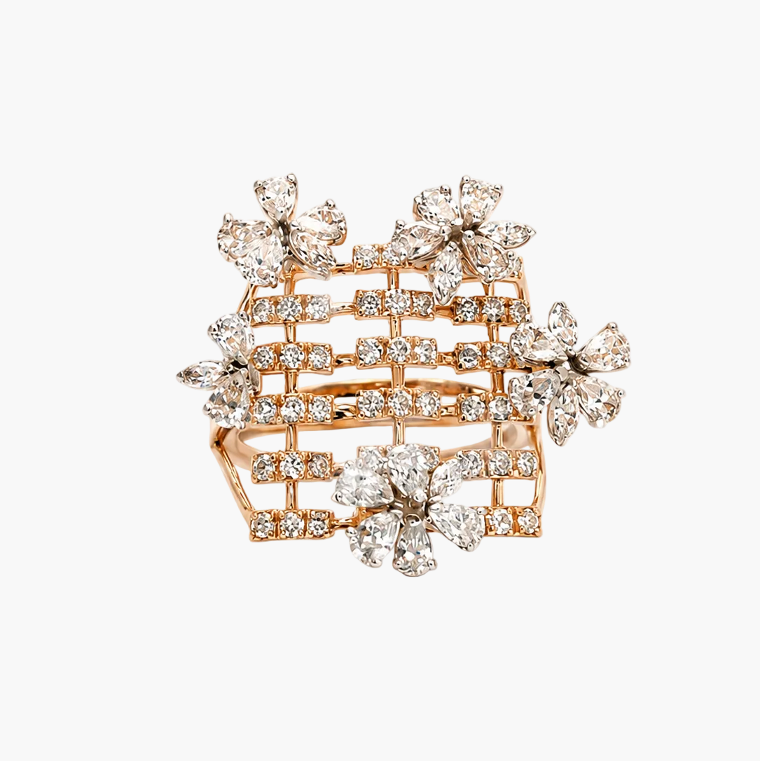 A wide, statement ring in rose gold featuring a grid-like basketweave structure paved with clear diamonds, accented by floral diamond clusters on the top and front, set against a plain white background.