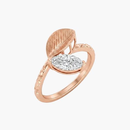 A rose gold ring featuring a marquise-cut clear diamond set within a leaf-shaped bezel, on a clean white background.