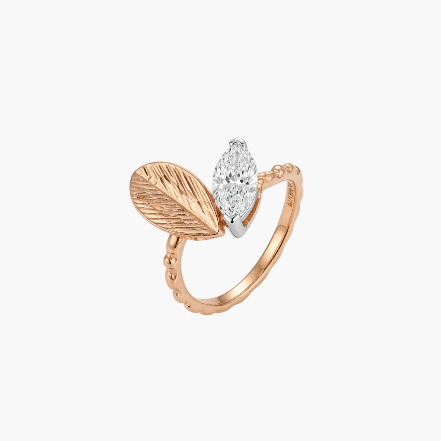 A rose gold ring featuring a textured leaf motif and a marquise-cut clear gemstone, shown on a clean white background.