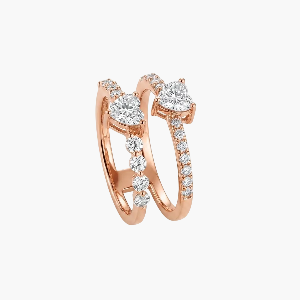 A pair of rose gold wedding bands with heart-shaped diamond settings and pavé accents, displayed on a clean white background.